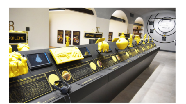 Museum display of yellow tactile replicas of ancient artefacts with braille labels and headphones