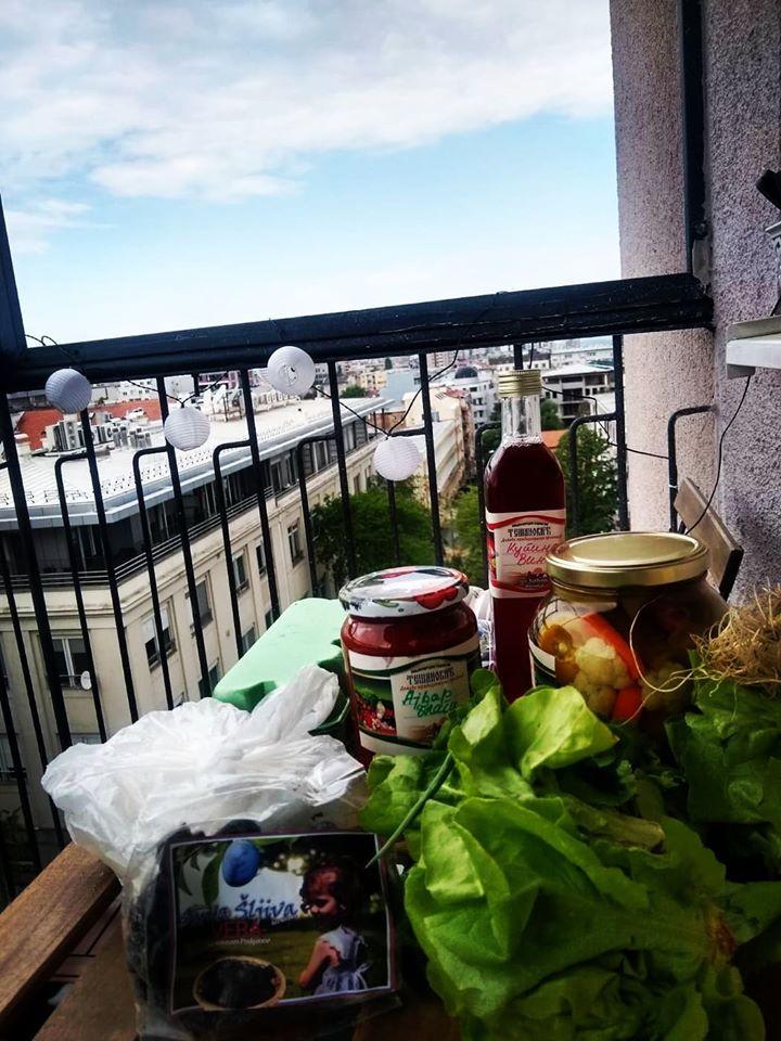 Jars of preserves and fresh vegetables packed on a balcony, ready for delivery