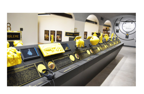 Museum display of yellow tactile replicas of ancient artefacts with braille labels and headphones