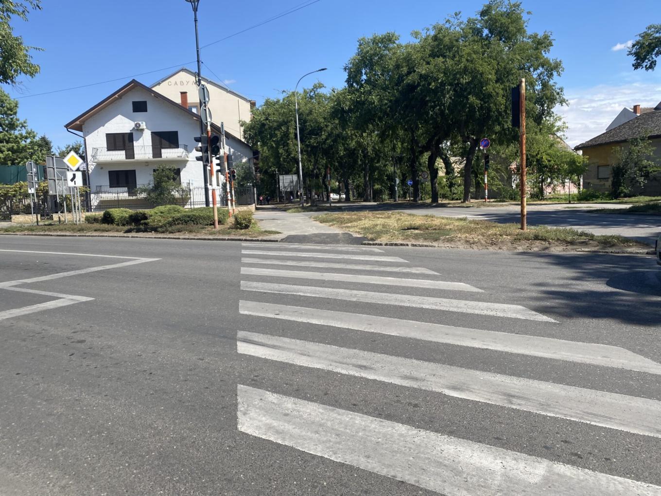 A pedestrian crossing on a wide street, with houses behind